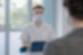 A Man in White Scrub Suit Wearing White Face Mask Talking to a Patient for Nephrology Care.