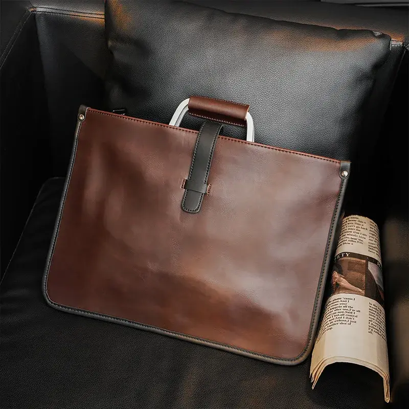 Brown crazy horse leather briefcase on a black chair.