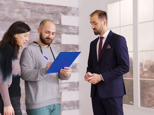 Couple signing check-in documents at a vacation rental while host assists, part of a professional Airbnb Concierge Service for guest support.