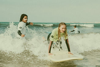 Surf instructor pushes student in wave, on a surf lesson in peniche