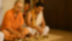 Two men in traditional attire sit cross-legged, eating from plates. The background has religious decor. Calm, serene atmosphere.
They are performing online Brahmin Bhojan Service with MahaTarpan.