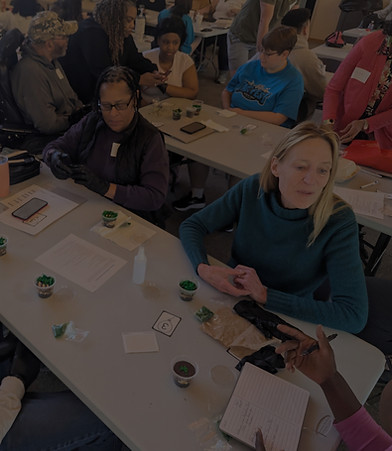 Workshop participants engaged in a hands-on table activity, preparing small plant projects.