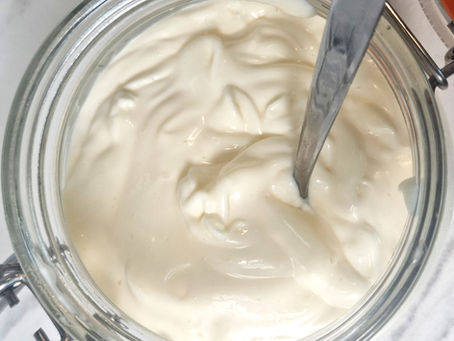 top down view of a glass jar or thick creamy mayonnaise with a spoon in it