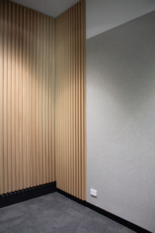 Light grey acoustic wall panel adjoining vertical timber feature wall.