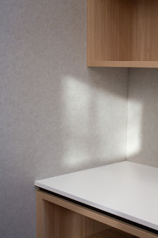 Close-up of light grey acoustic wall panel behind custom timber cabinetry.