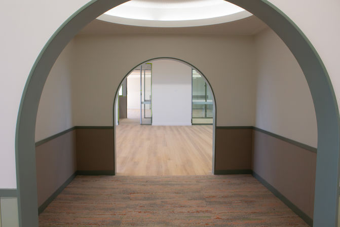 Kindergarten corridor with arched openings and acoustic wall panels at Carlo Acutis Catholic Primary School.