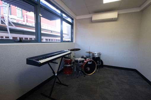 Music practice room with acoustic wall panels surrounding keyboard and drum kit.