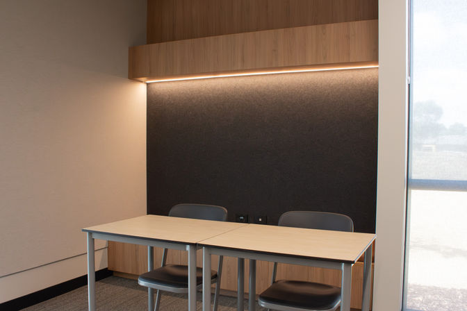 Collaborative study nook lined with acoustic wall panels and warm LED strip lighting. 