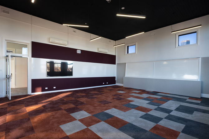 Collaborative learning space featuring WriteWall® WWL whiteboards and deep red and light grey acoustic wall panels.