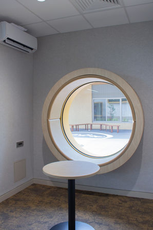 Circle window seating nook with grey acoustic panel wall
