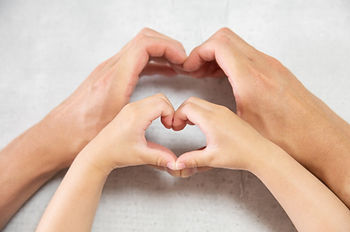child's hands mimicking adult's hands making a heart shape
