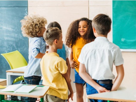 Group of children standing and chatting in a classroom.