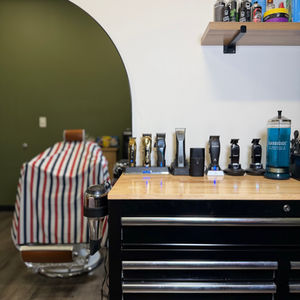 Photo of Barber station, including clippers, Barbicide, and a Barber chair and cape.