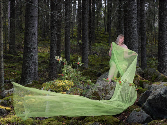 nainen metsässä istuu kivellä vihreä kangas