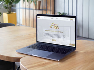 אתר אינטרנט מוצג על מסך מחשב שולחני המונח על שולחן, עם עיצוב ממשק ברור ודף בית גלוי