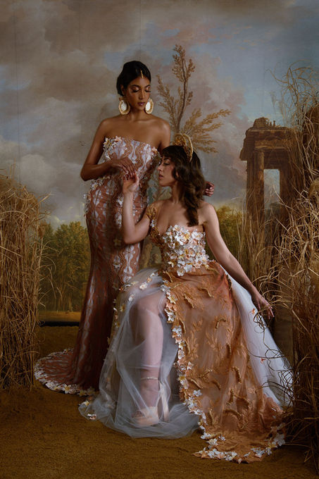 Maison M'Elise - Maria & Vanita gowns together: Maria's ochre ball gown with raffia details & Vanita's high-split fishtail with hand-painted flowers."