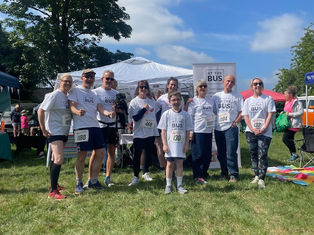 A team of white runners including one child wearing white AT The t-shirts at a sporting event