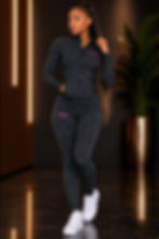 Woman wearing the Biilow Movement Collection Pulse Set, featuring a black full-zip performance jacket and matching high-waisted leggings with a vibrant multicolor speckled design for active comfort and style.