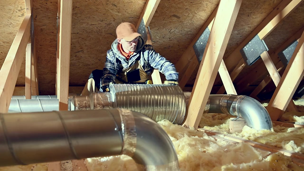 Air duct technician checking leaking ducts inthe attic. Attic insulation is spread around the attic.