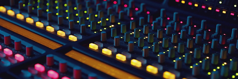 close up photo of a sound mixing board with brightly colored lights and many knobs