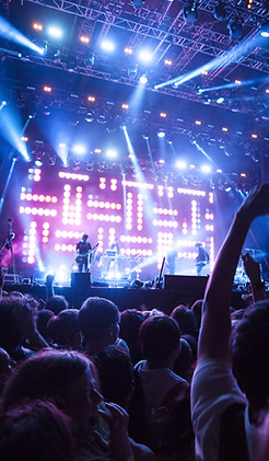 large concert crowd rocking out under blue and purple stage lights