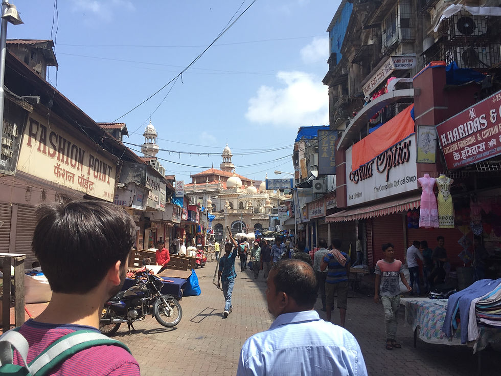 The view down a crowded street in Mumbai with various shops on either side.