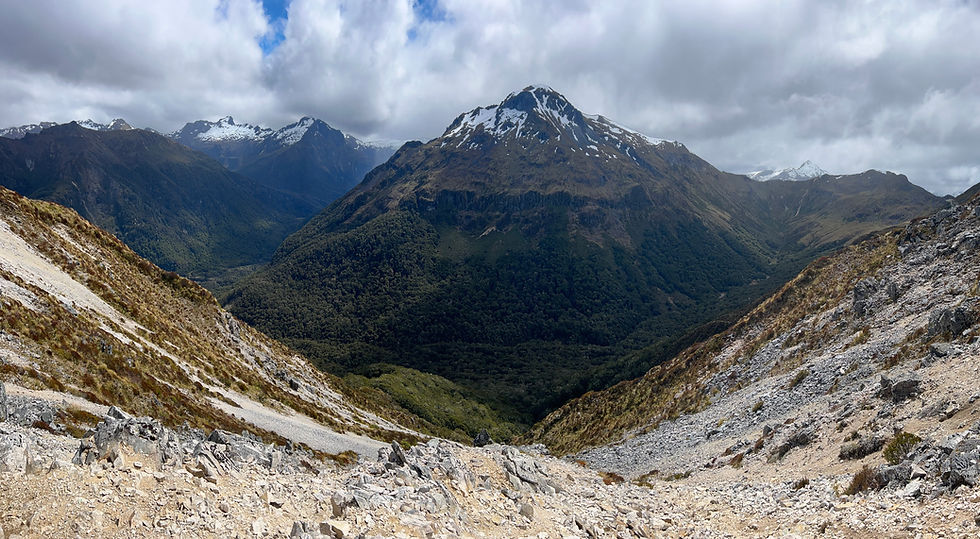 A large, green mountain can be seen jutting up from a valley between two rocky mountainsides.