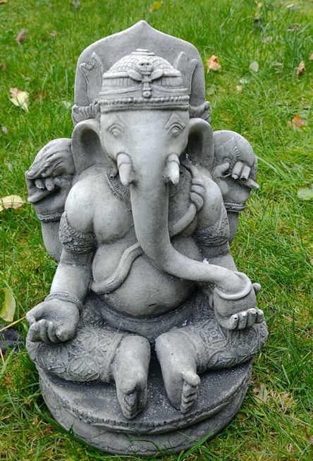 Stone statue of Lord Ganesh, god of wisdom, in a lush outdoor setting.