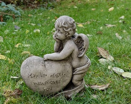 Stone cherub statue with heart, May the angel watch over you, grass background