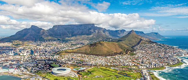 Panoramic daytime view of Cape Town from a distance, showcasing Table Mountain, city skyline, and the natural beauty of South