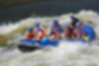 Rafting group navigating white water rapids on the Zambezi River, surrounded by rocky cliffs.