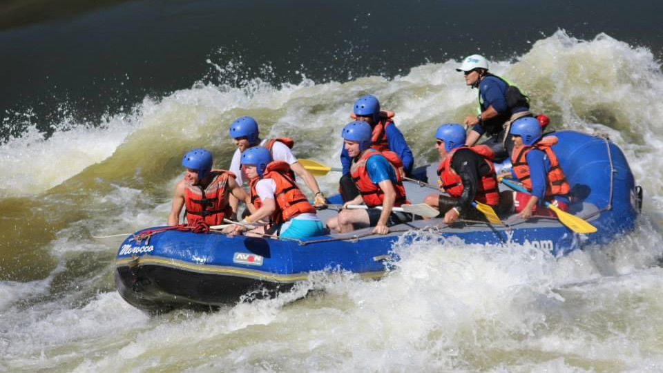 Rafting group navigating white water rapids on the Zambezi River, surrounded by rocky cliffs.