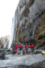 Group of tourists swimming at the base of Victoria Falls surrounded by rocky gorge walls.