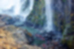 Traveler swimming in the spray pool beneath Victoria Falls with mist rising in the background.