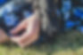 A horizontal image of a black Labradoodle's paw across a woman's hand symbolizes their strong bond and connection.