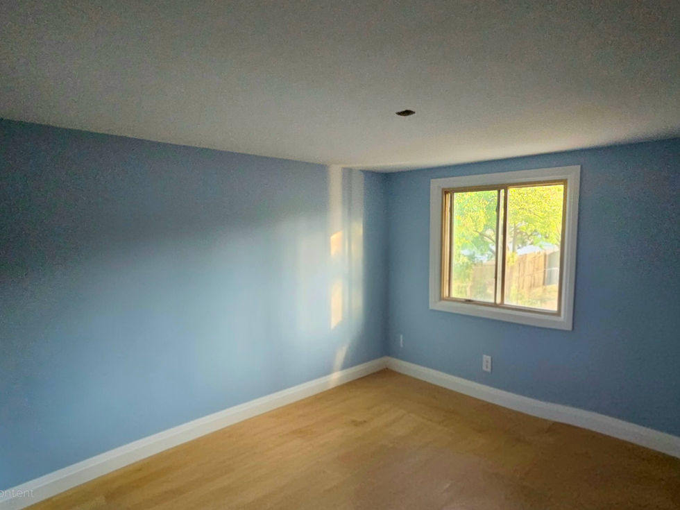 Empty room with light blue walls, window, and wooden floor.