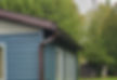 New Brown eavestrough installed on a house with blue siding.