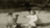 A child in a white dress crouches outside, surrounded by a hen and chicks, reaching out to them. The setting is gravel, mood is curious.