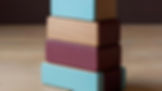 Stack of four building blocks with tan, teal, and maroon accents