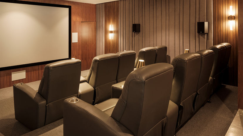 Home theater con pantalla de gran formato, iluminación ambiental y asientos reclinables, diseñado por un diseñador de interiores especializado.