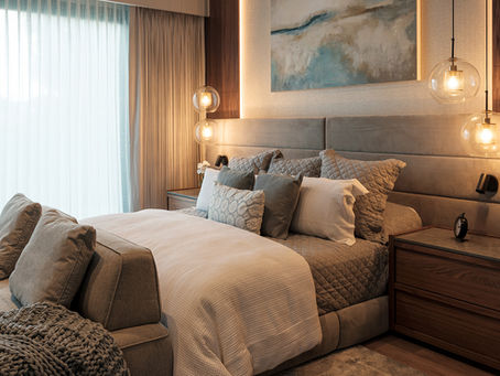 Diseño interior de una recámara con lámparas colgantes, mobiliario de madera, texturas suaves en la cabecera y la ropa de cama.