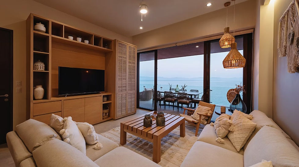 Sala con mobiliario cálido y acceso directo a una terraza frente al mar, diseñada como una extensión interior de salas abiertas a la brisa marina.