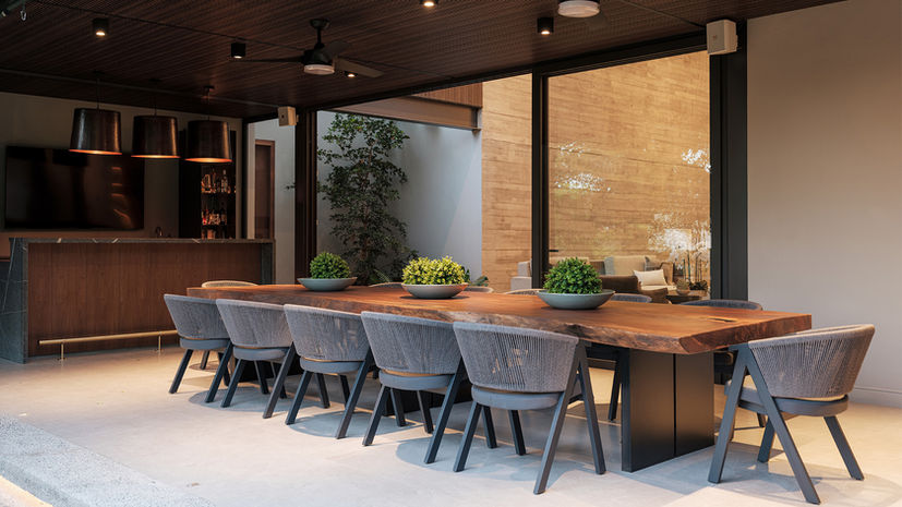 Terraza techada con comedor de madera y barra.