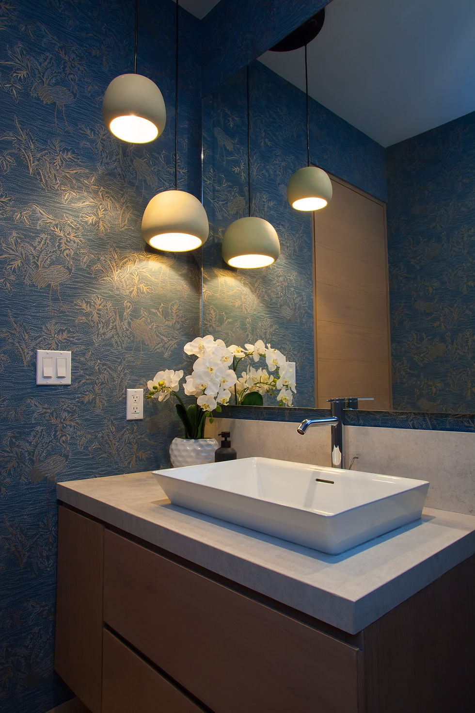 Baño moderno con iluminación tenue y papel tapiz azul que aporta serenidad al espacio