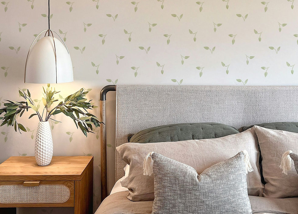 A beautifully staged bedroom scene with a minimalist wallpaper design featuring a white background and scattered pale green leaves