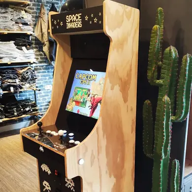 Détail d’une borne en bois naturel installée près d'un mur végétal, jouable à deux sur des hits d’arcade des années 80-90