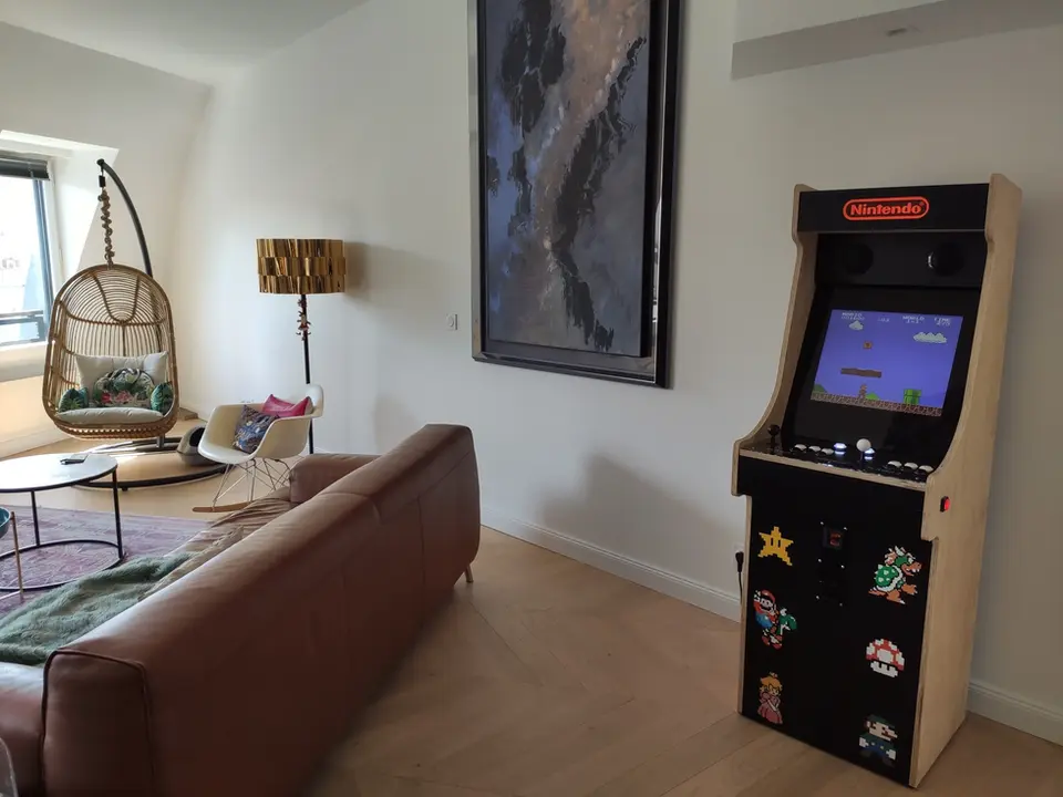 Borne d'arcade mario pixel dans un joli salon avec canapé en cuir et une nacelle