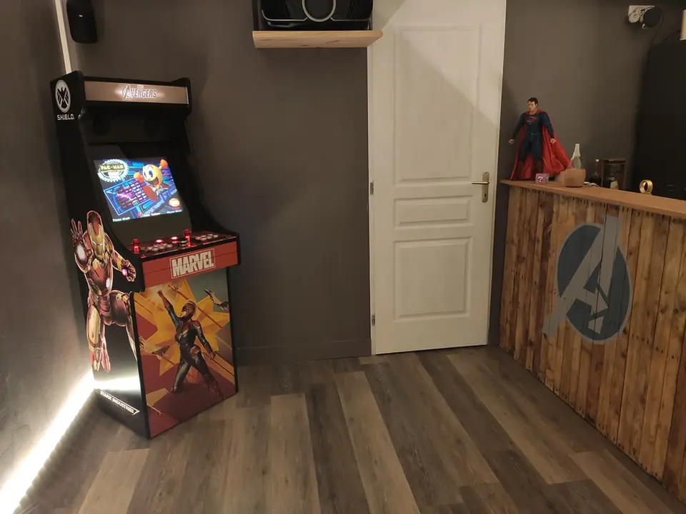 Borne d'arcade dans une man cave retro gaming avec un espace bar