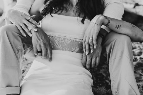 Black and white engagement photo of a couple's hands while they are embracing at the beach in Niagara