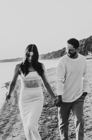 Engagement photo of a couple playfully walking at the beach in Niagara